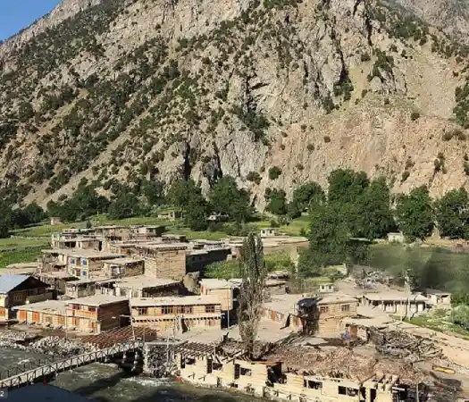 A timber and stone village with a footbridge over the river