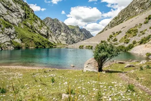A turquoise mountain lake ringed by rocky green slopes