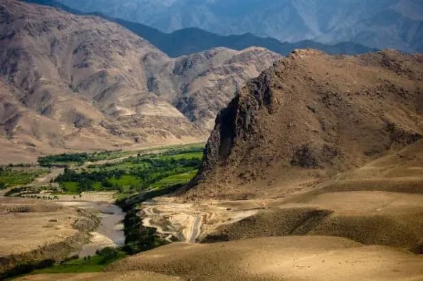 A green river valley between dry mountain slopes in Laghman