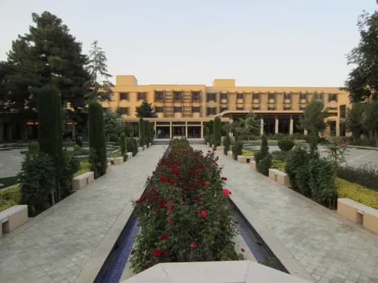 A hotel garden walk lined with rose beds and clipped trees