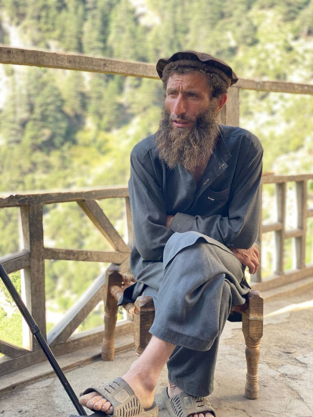 An elder seated on a hand-turned wooden stool on a timber veranda