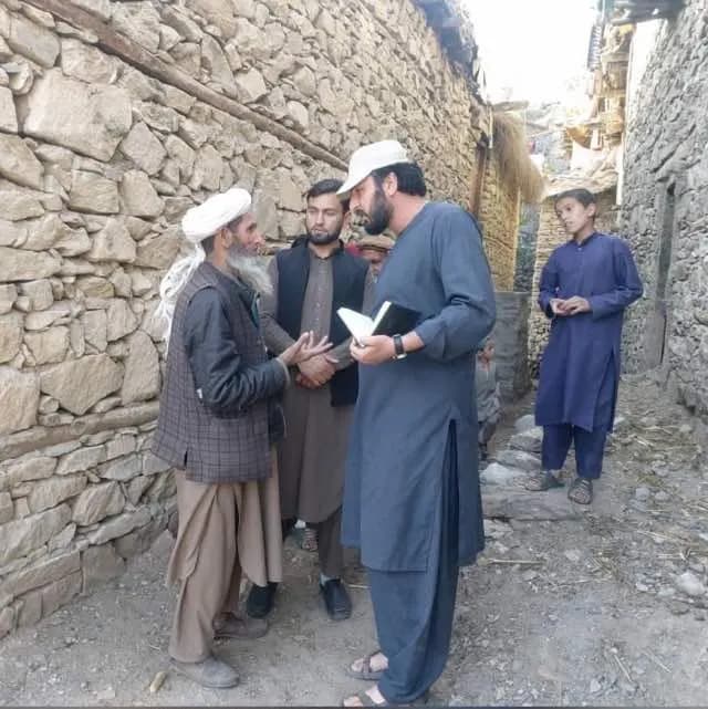 Abdulrahman Chonish talking with a white-bearded elder in a stone-walled village lane
